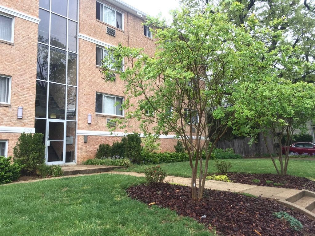 A large brick apartment building with a lush green lawn in front of it.