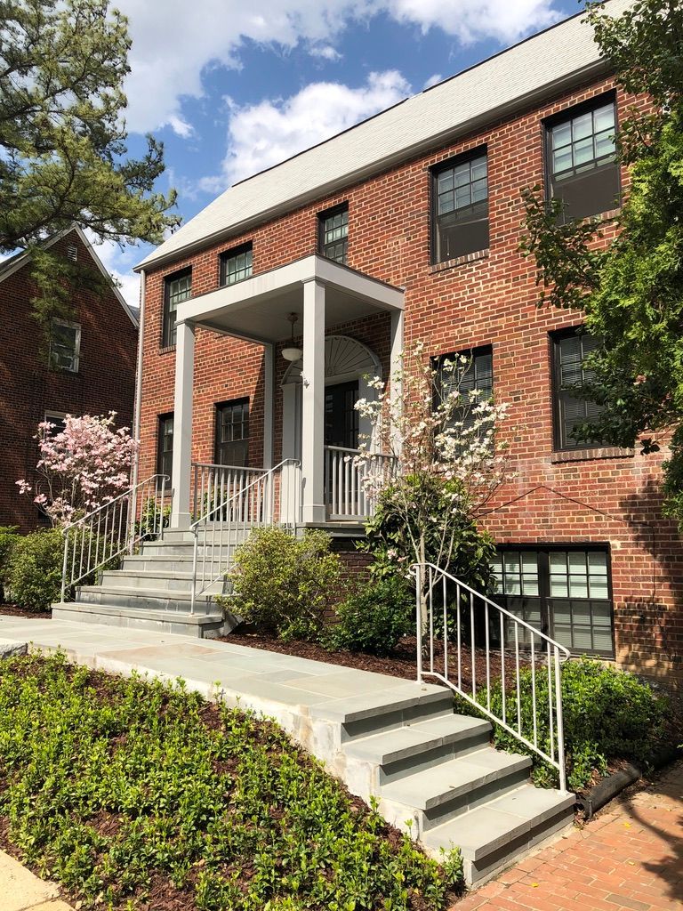 A large brick building with stairs leading up to the front door.