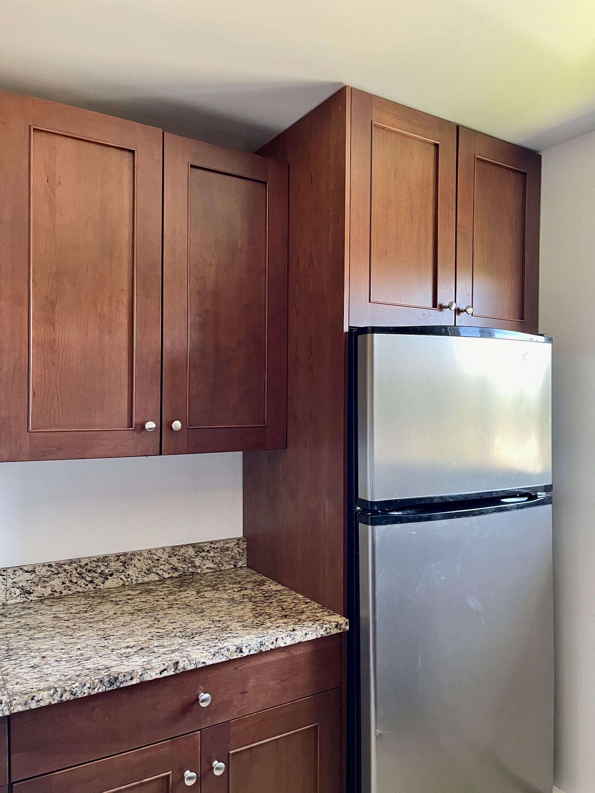 A kitchen with wooden cabinets and a stainless steel refrigerator