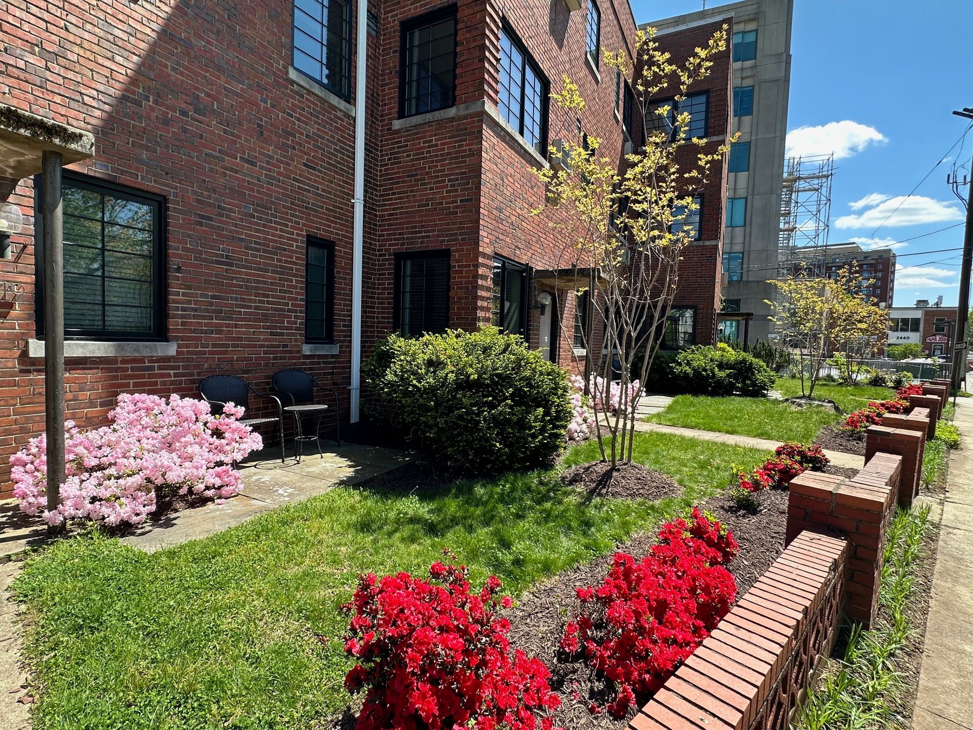 A brick building with a lush green lawn and flowers in front of it.