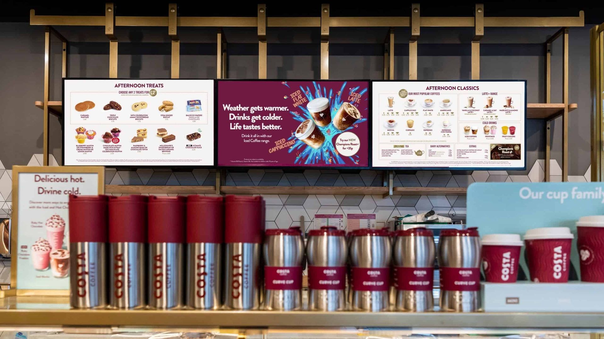 Coffee shop shelf with maroon canisters and cups beneath menu boards and a central promotional sign