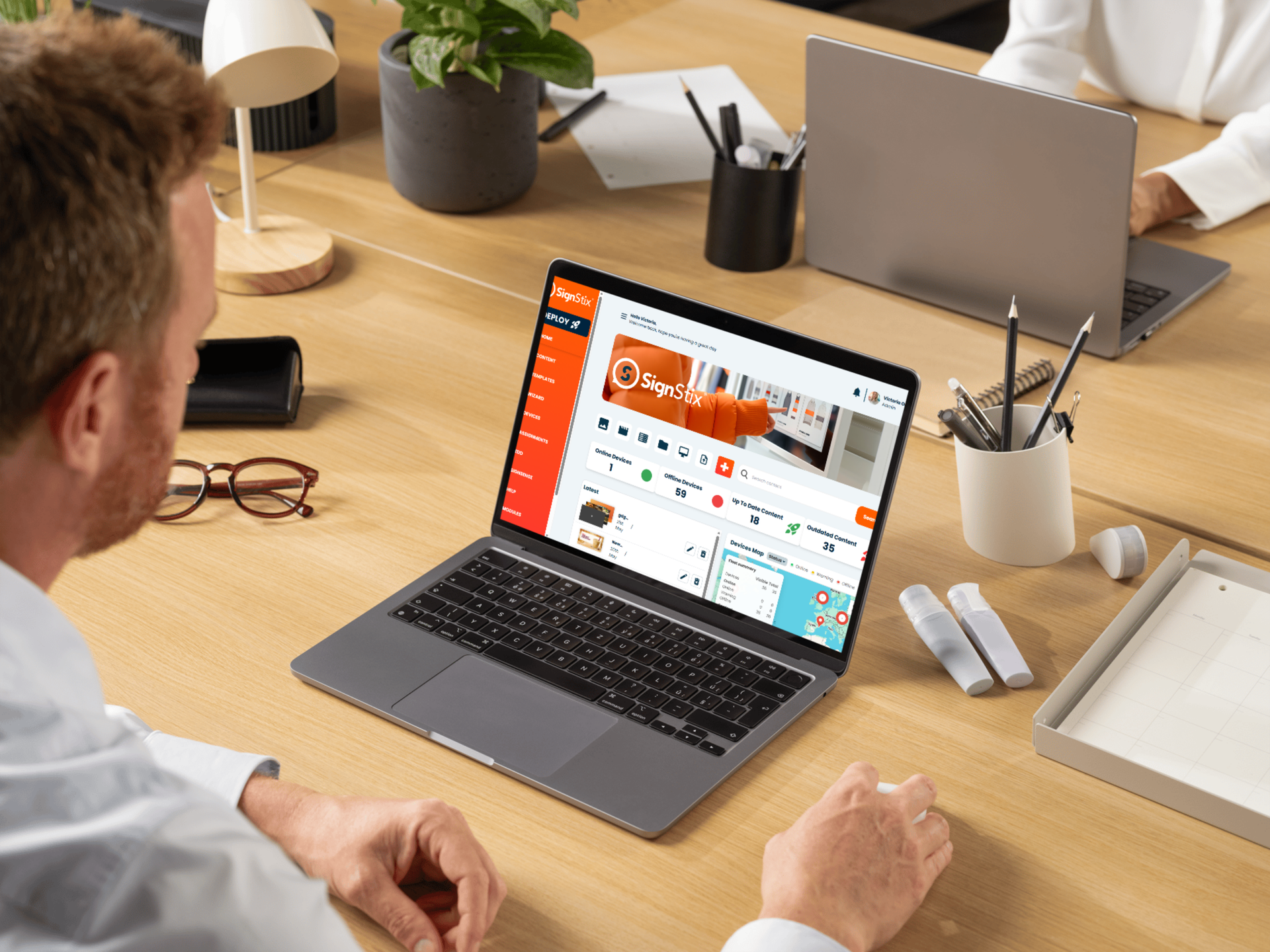 Person working at a desk on a laptop displaying a website, with office supplies and a plant nearby.
