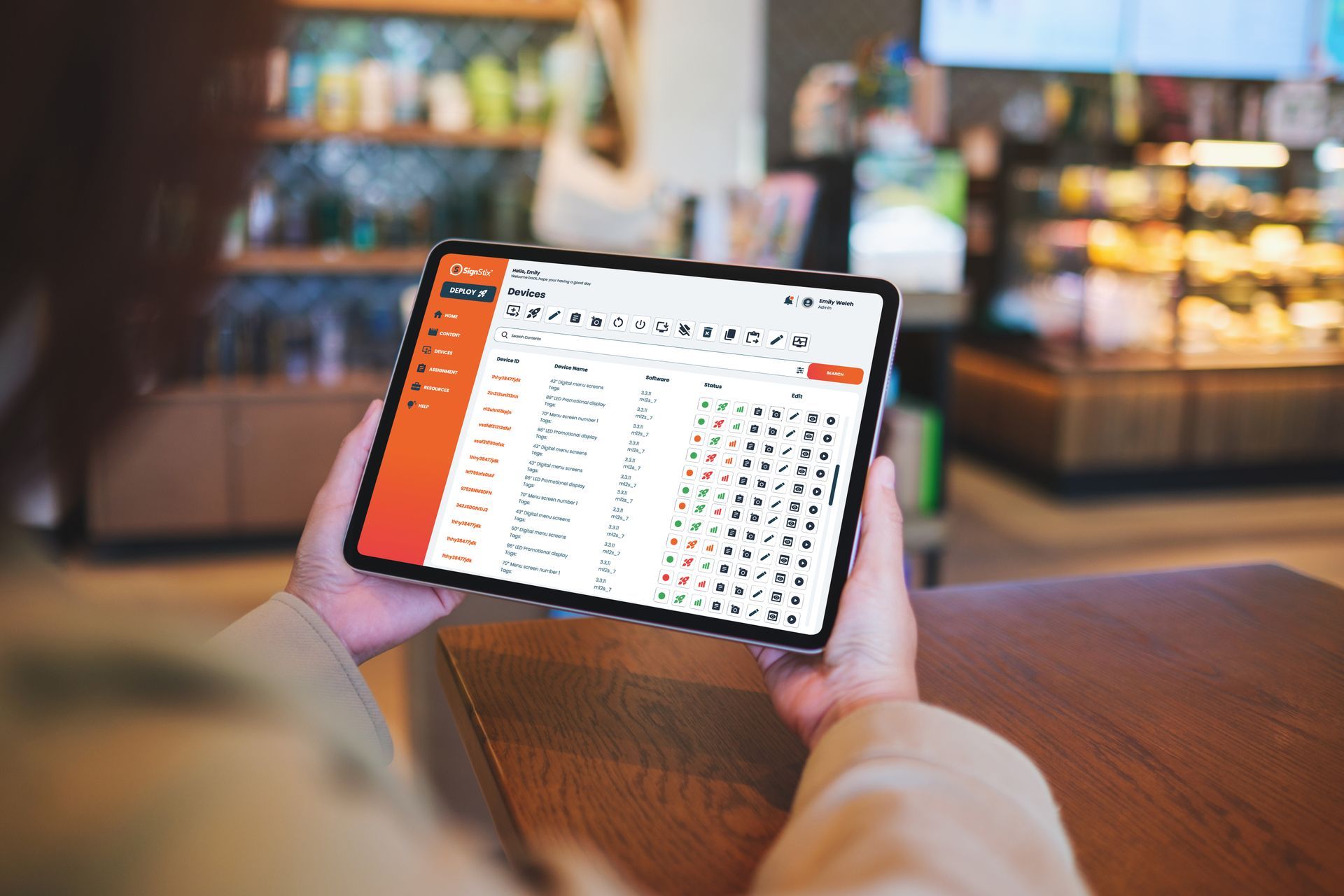 Person holding a tablet displaying a spreadsheet in a café with a blurred background