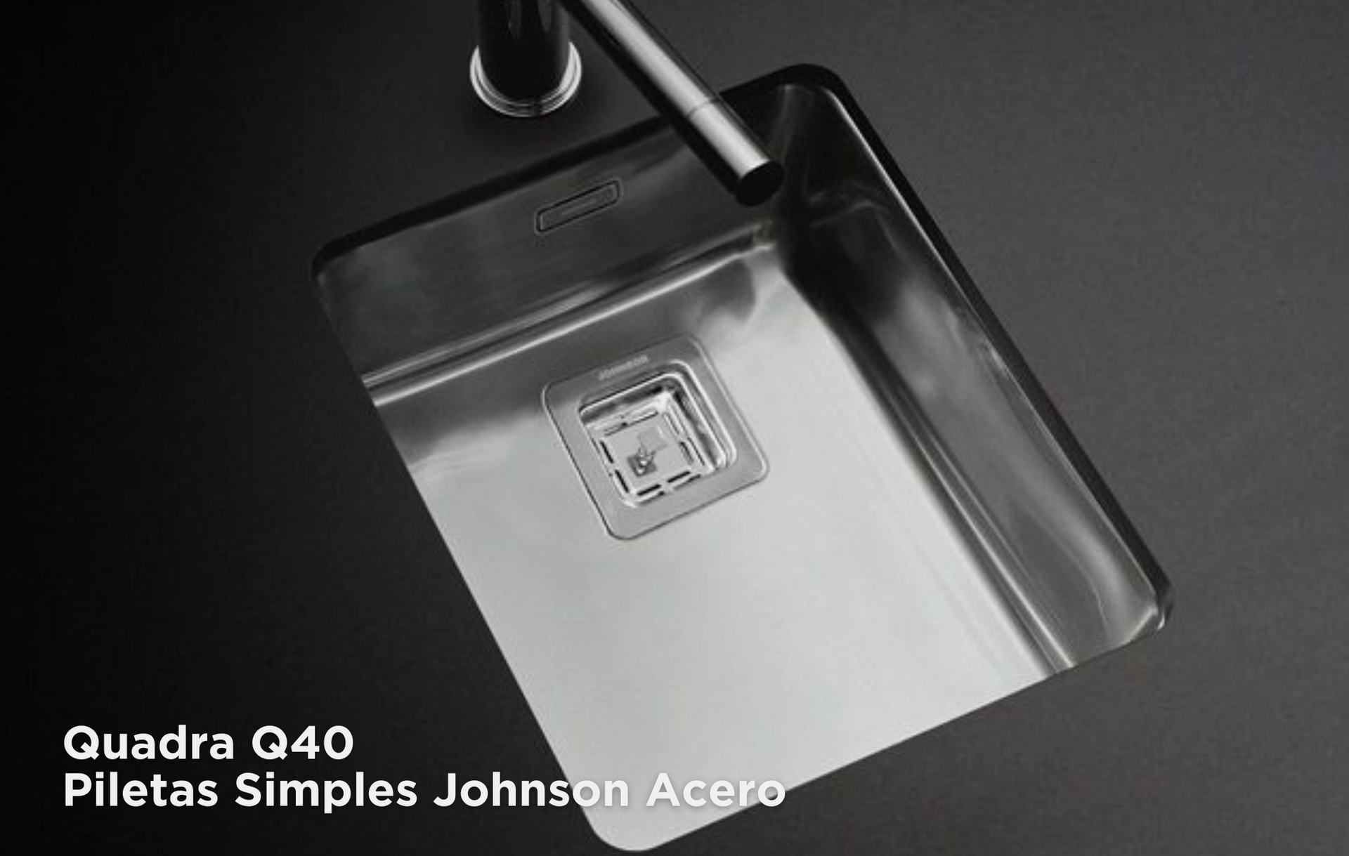 Lavabo de acero inoxidable con grifo cromado sobre una encimera oscura