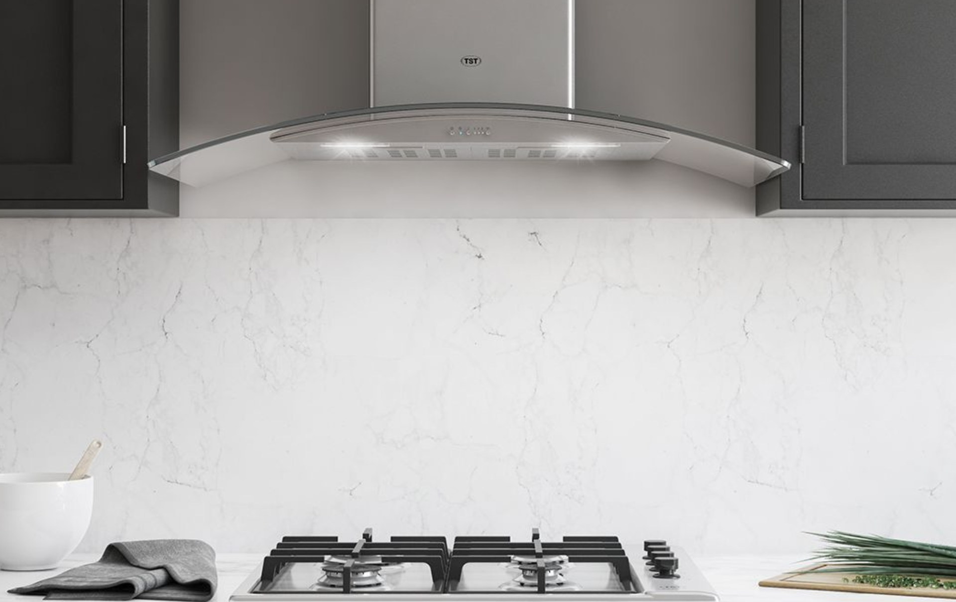 Cocina moderna con placa de cocción de acero inoxidable, campana extractora, armarios oscuros y salpicadero de mármol.