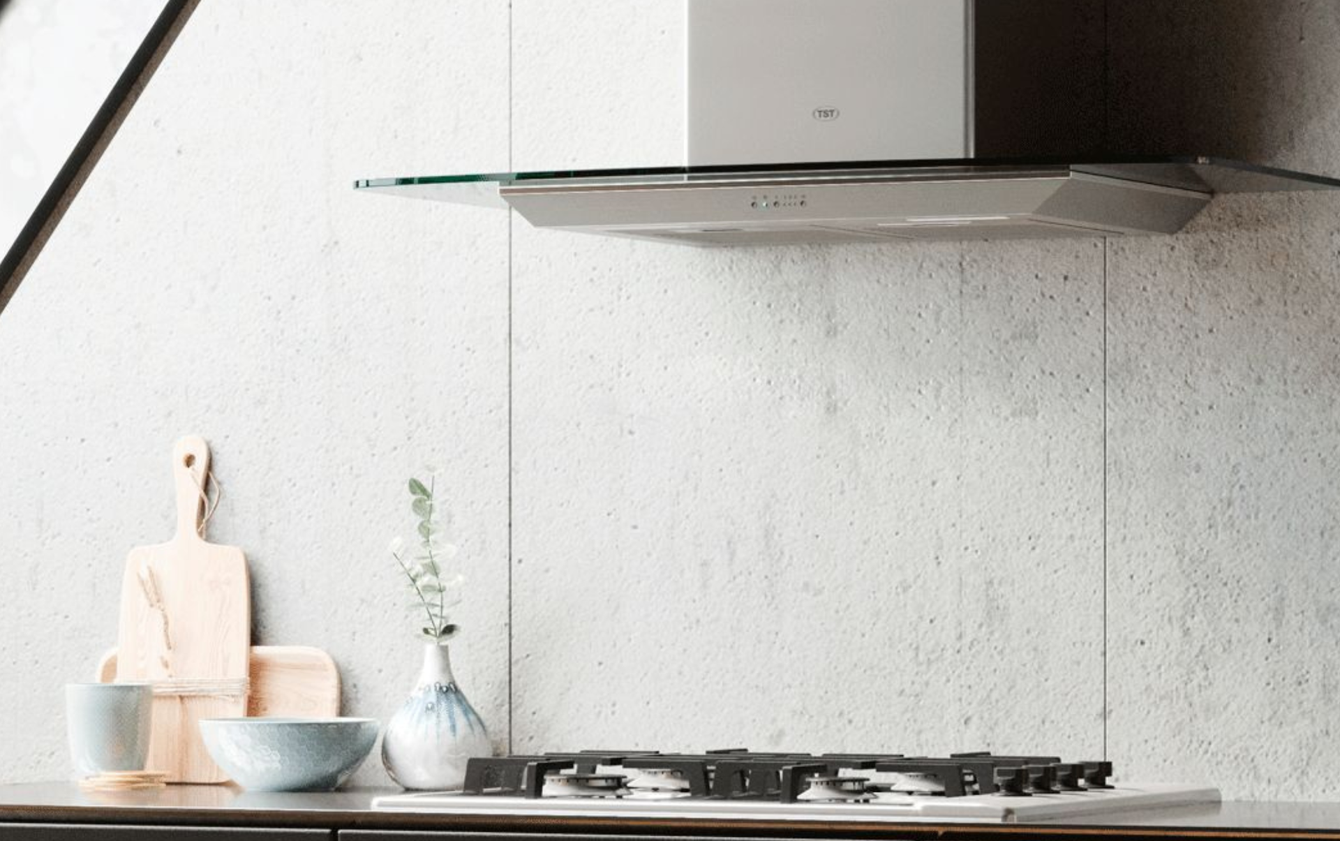 Encimera de cocina blanca minimalista con cuencos, tabla de cortar, jarrón y cocina de gas bajo una campana extractora.