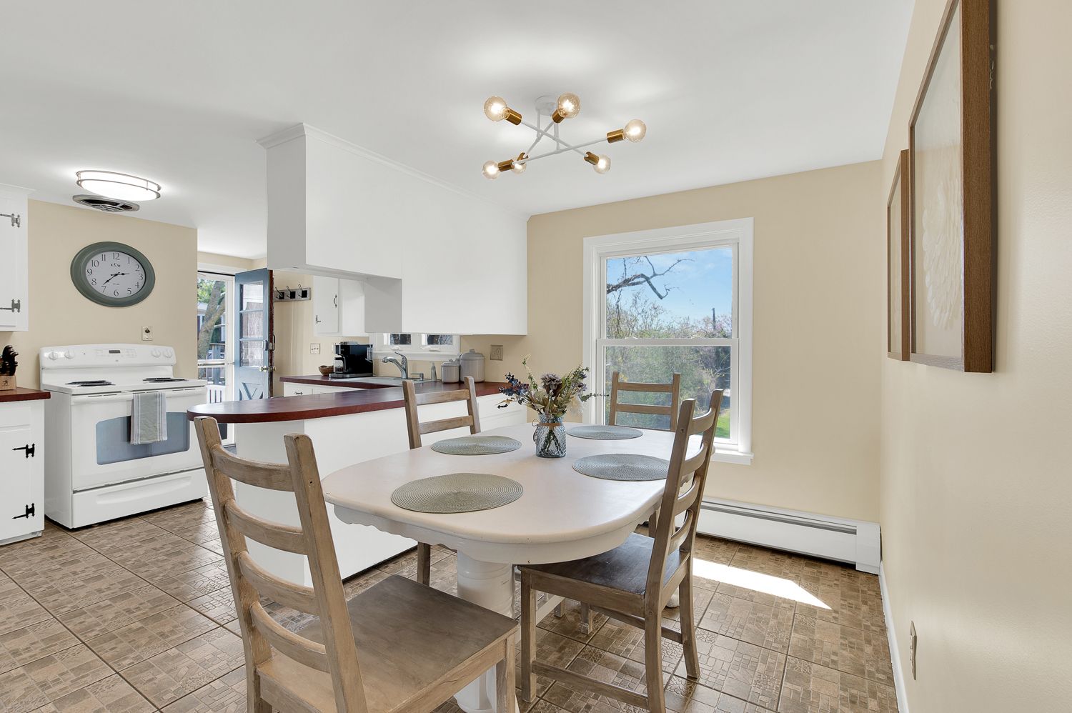 A kitchen with a table and chairs and a clock on the wall.