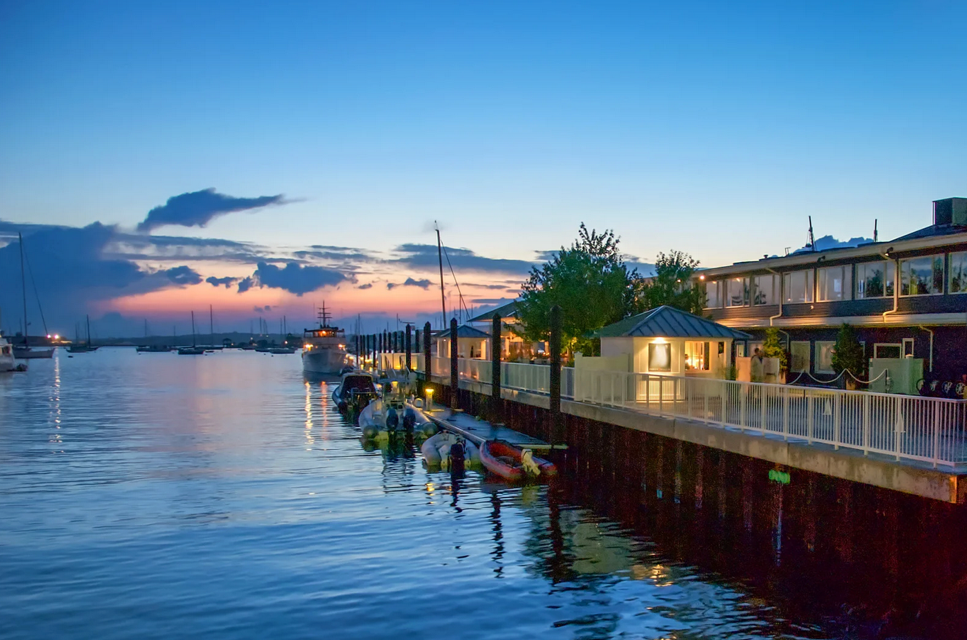 A dock with boats docked in the water at sunset.