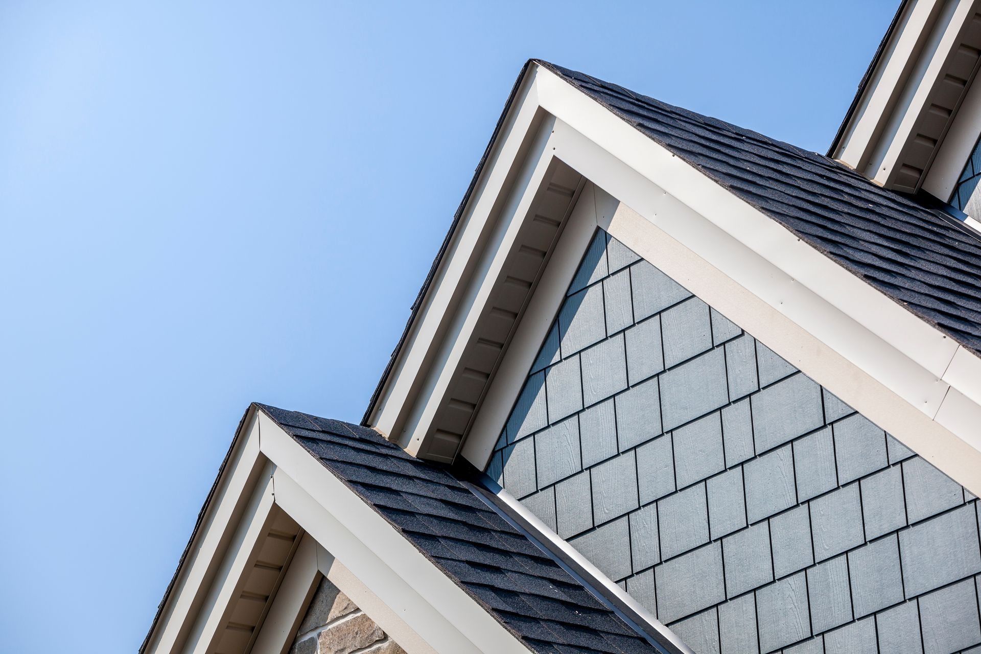 Toit et bardage triangulaires d'une maison se détachant sur un ciel bleu azur.