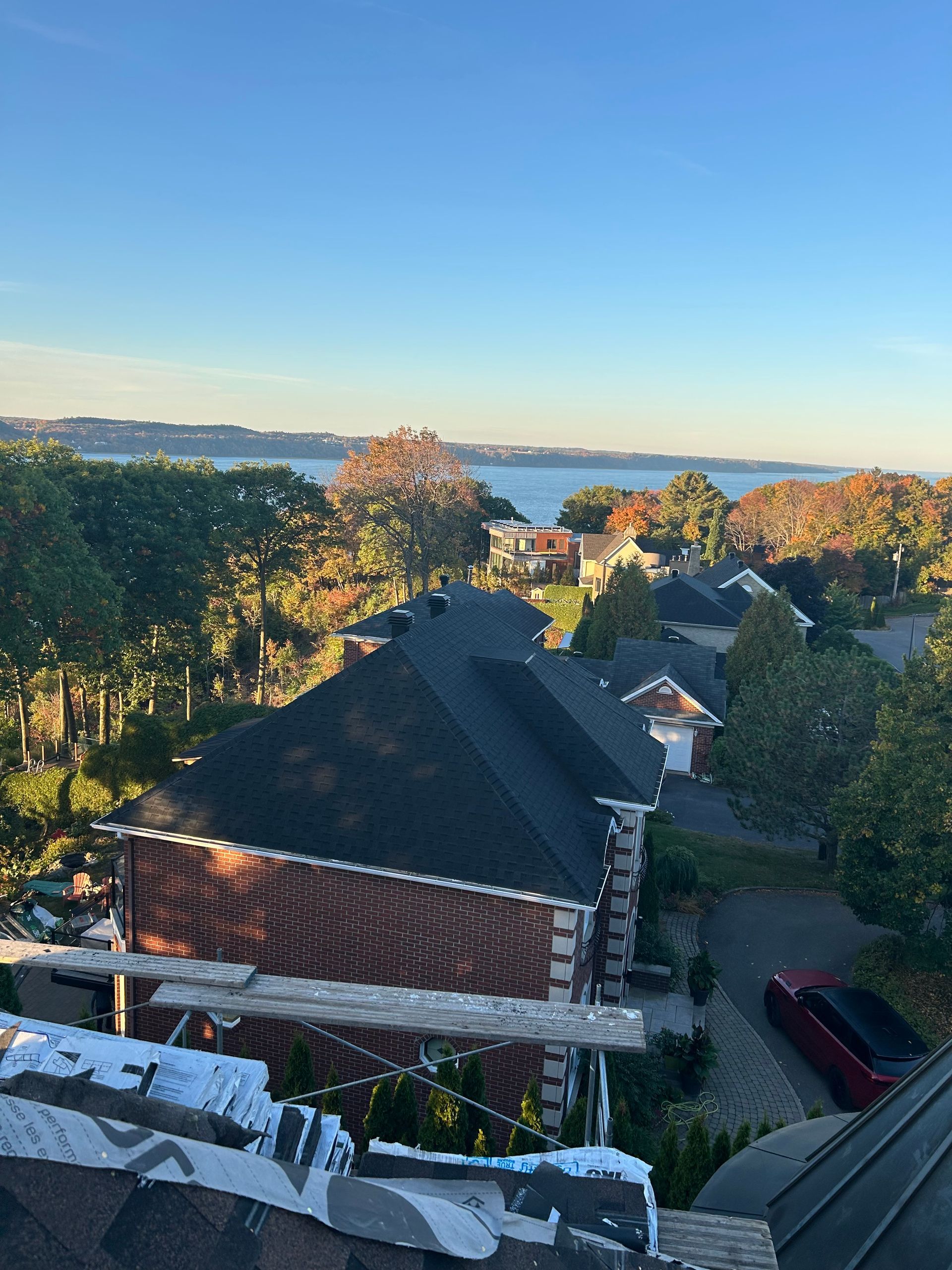 Vue depuis les toits de maisons, d'arbres et d'eau sous un ciel bleu, avec quelques feuilles d'automne.