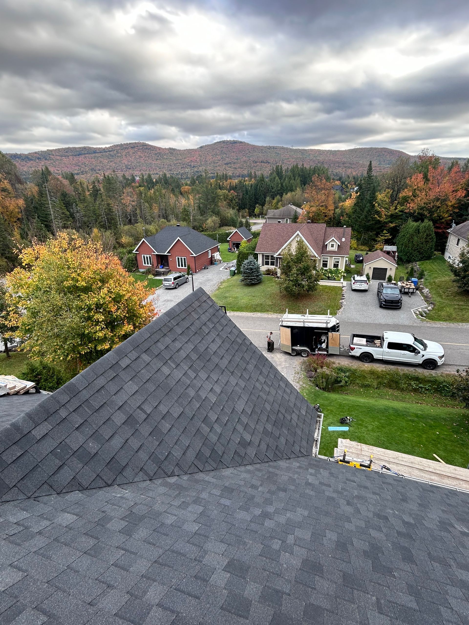 Un quartier résidentiel avec un toit fraîchement recouvert de bardeaux et un feuillage d'automne aux couleurs chatoyantes.