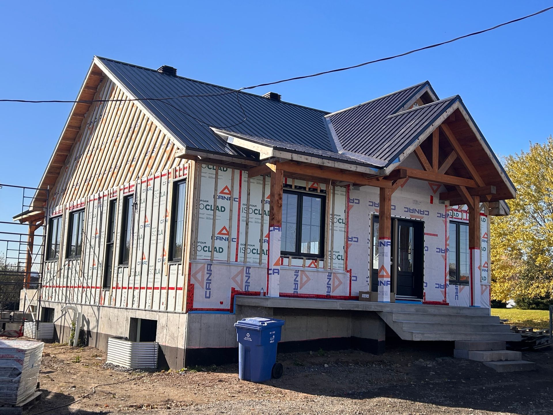 Maison en construction avec ossature bois apparente et bardage non fini.