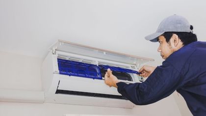 A man is working on an air conditioner in a room.
