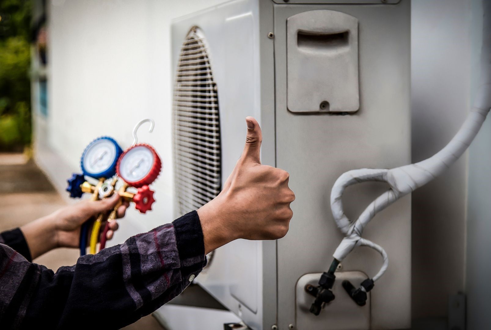 A person is giving a thumbs up while working on an air conditioner.