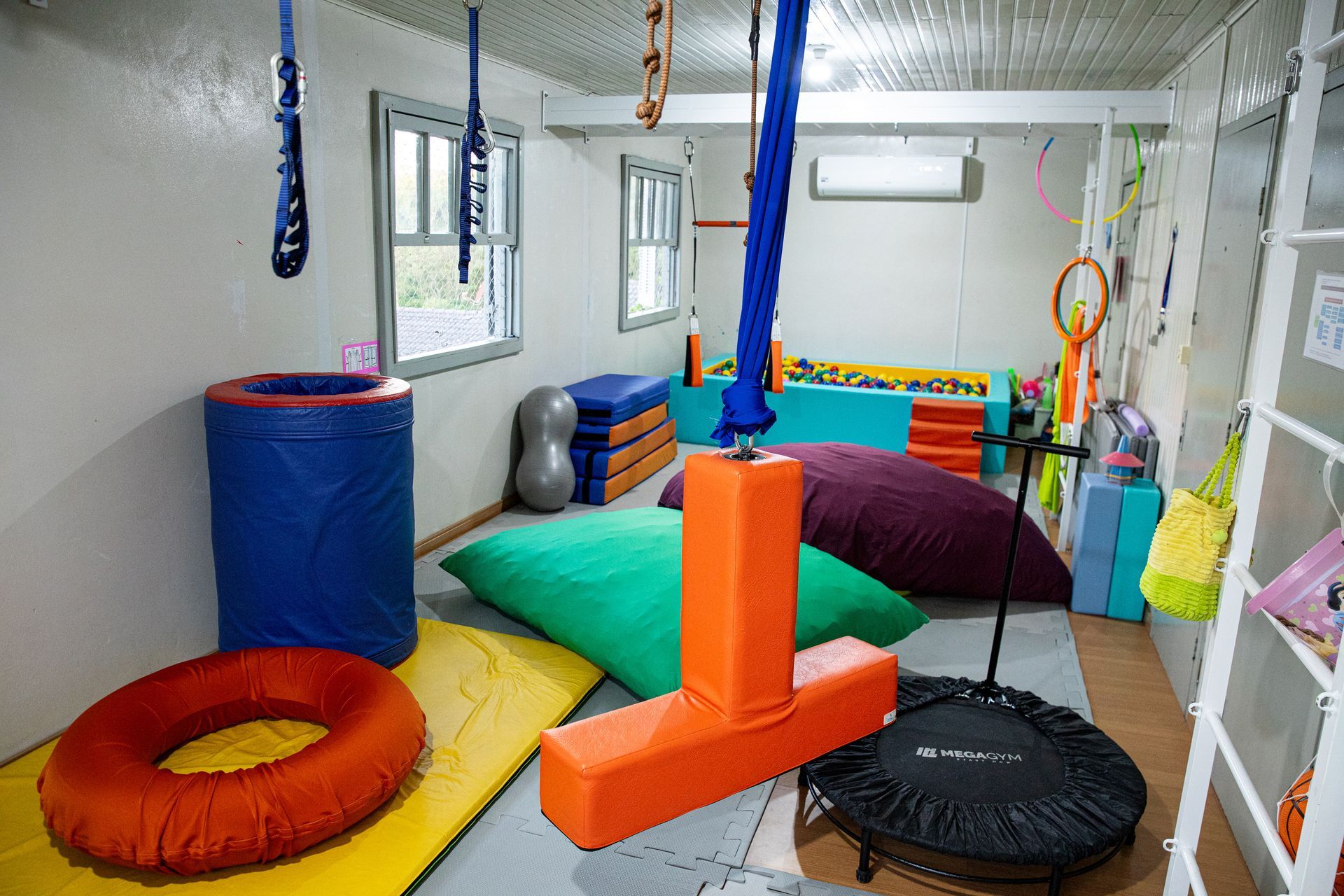 Ginásio sensorial interno com formas de espuma coloridas, balanços e equipamentos de equilíbrio