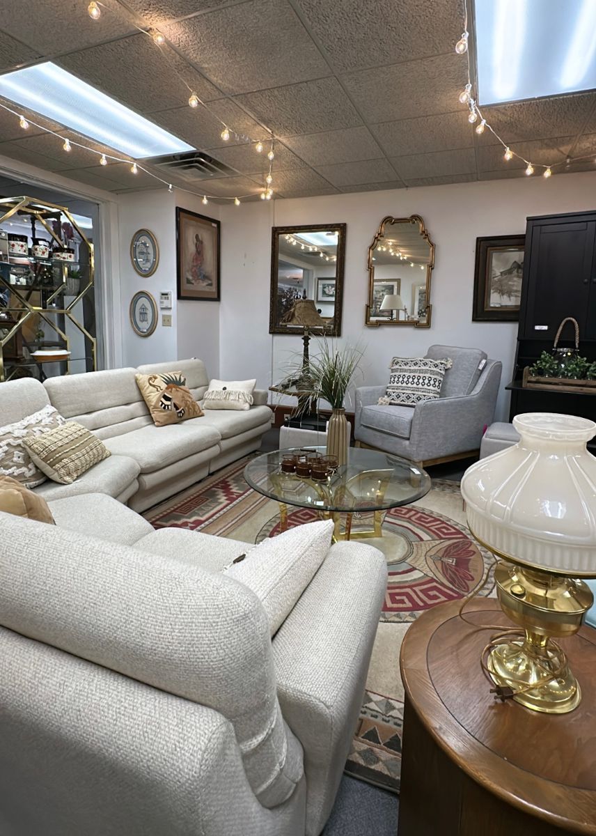 Elegant living room with white sofas, ornate decor, mirrors, and a glass coffee table