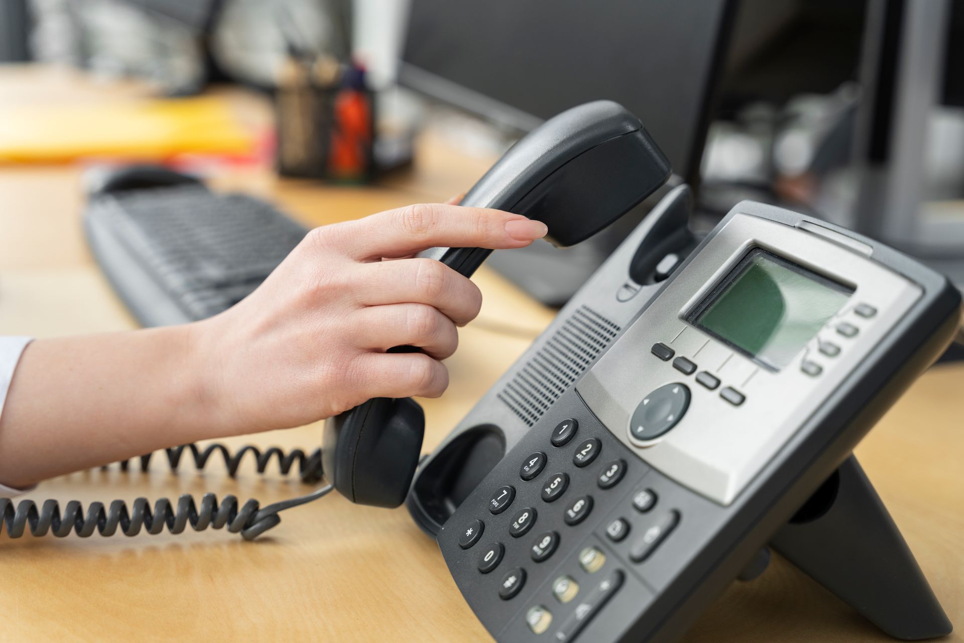 A person is talking on a telephone in an office.