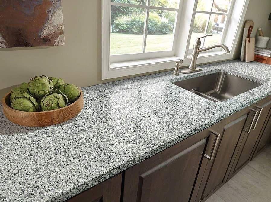 A kitchen counter with a sink and a bowl of artichokes on it.