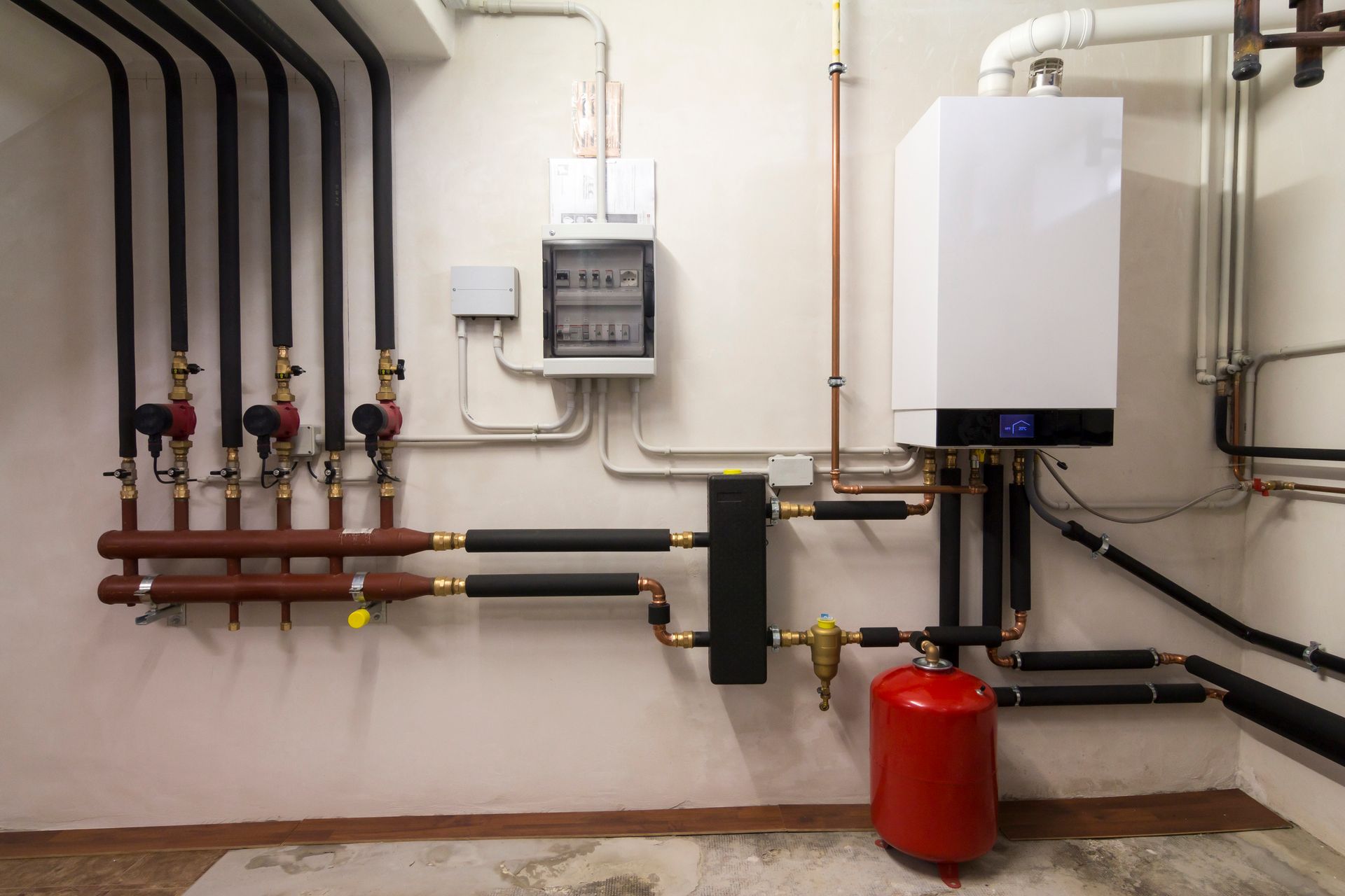 Gas boiler and different pipes in a room, part of a heating system installed by John E. Ruth Company