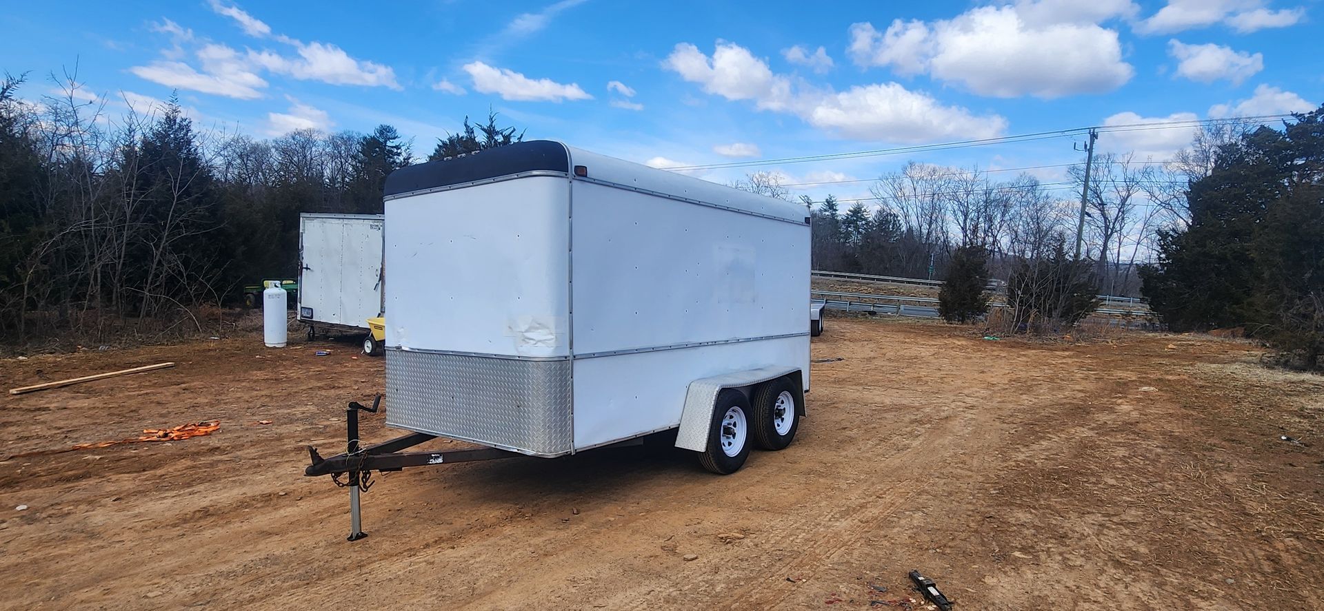 A white trailer is parked in a dirt field.