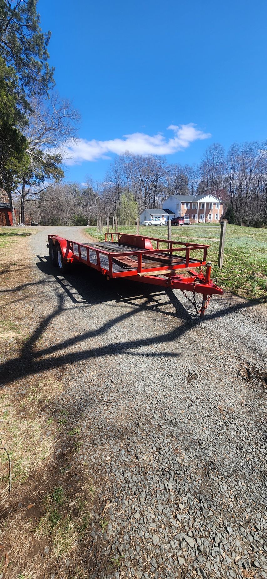 A red trailer is parked on the side of a gravel road.