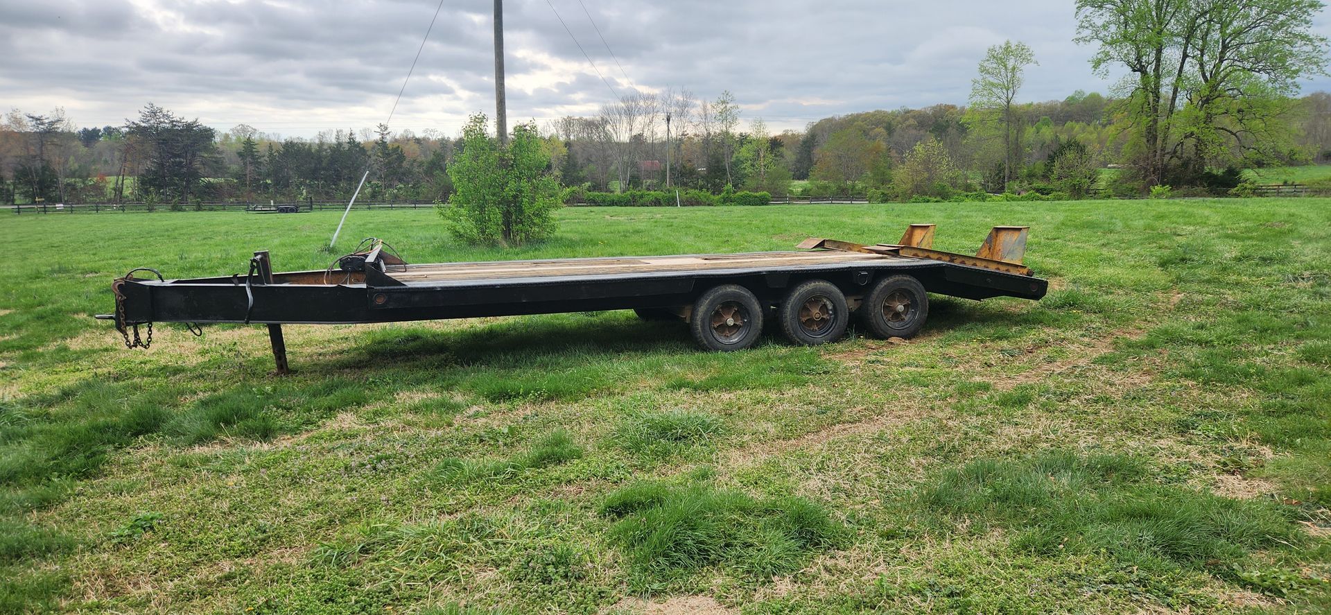 A trailer is sitting in the middle of a grassy field.