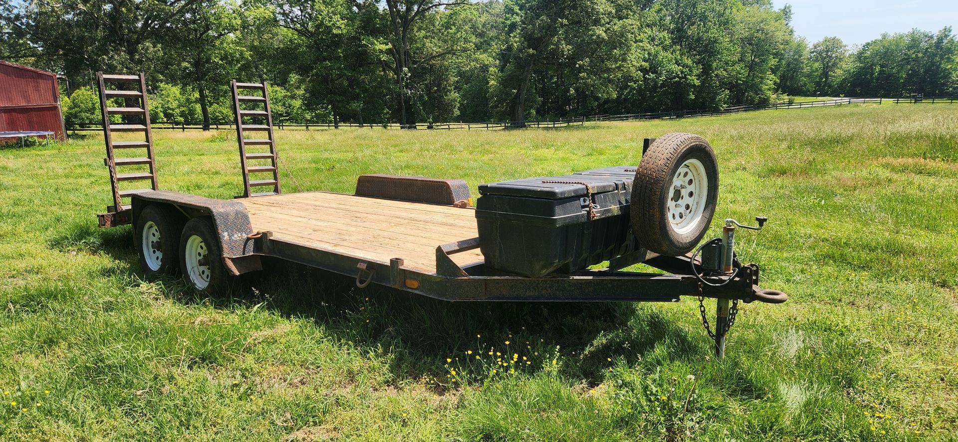 A flatbed trailer is parked in a grassy field.