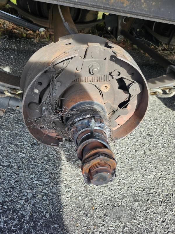 Severely damaged truck wheel hub with visible brake components. Metal debris, rust, and exposed mechanical parts.