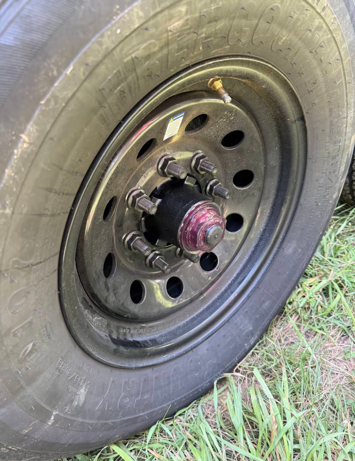 Black trailer tire and wheel with a flat tire.