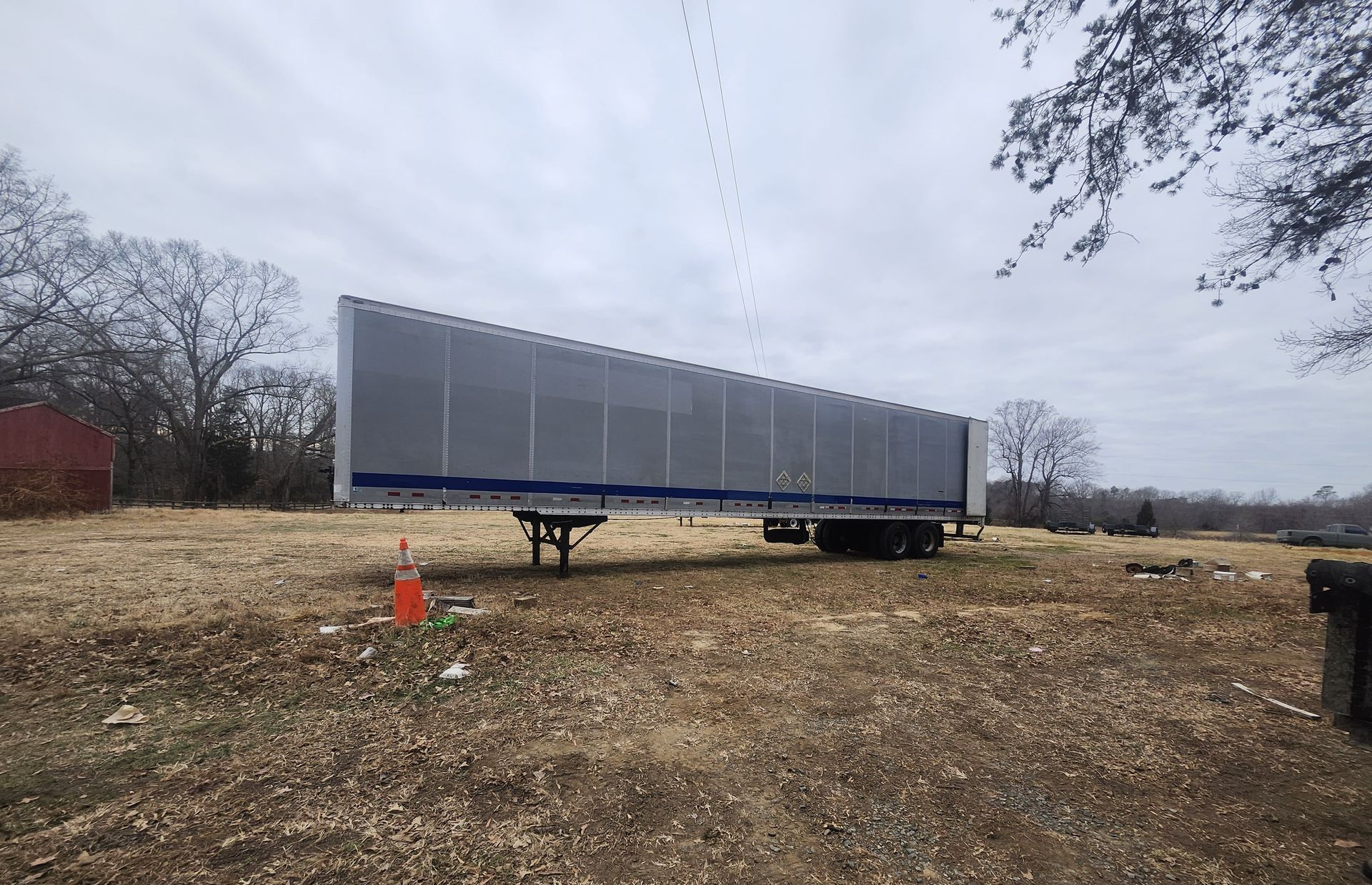 Flatbed trailer parked in a field with a cloudy sky overhead.