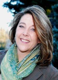A woman wearing a scarf and earrings is smiling for the camera.
