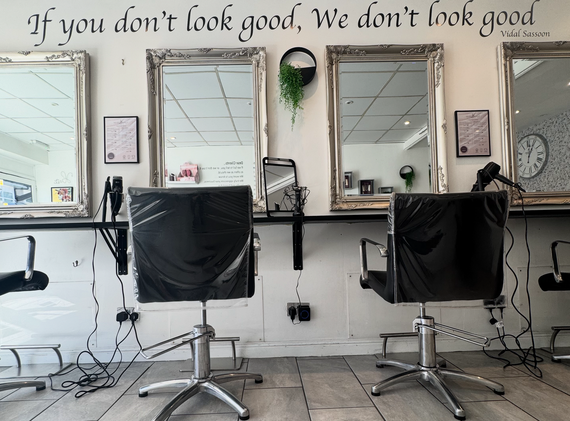 A salon interior featuring two black styling chairs facing wall mirrors
