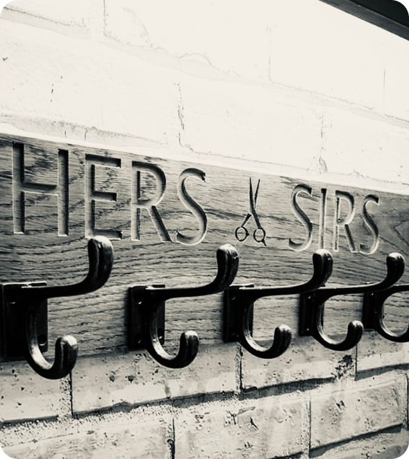 A wooden wall rack with black metal hooks, engraved with the words