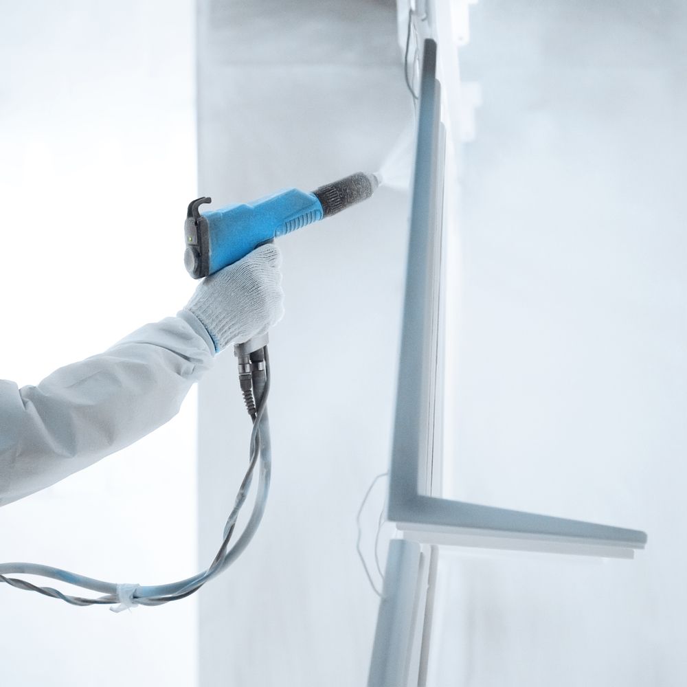 A Gloved Hand Holds a Blue Paint Spray Gun, Applying a Coat of Paint — Betts Welding Pty Ltd In Moss Vale, NSW