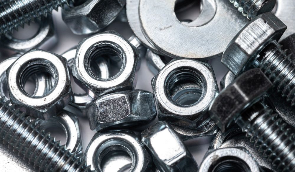 A Pile of Nuts and Bolts on A White Surface — Betts Welding Pty Ltd In Moss Vale, NSW