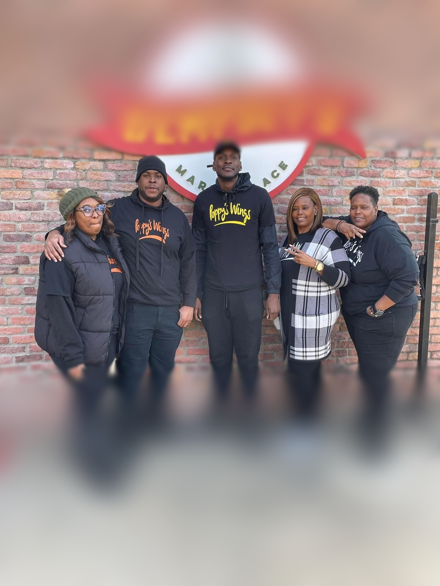 A group of people are posing for a picture in front of a brick wall.