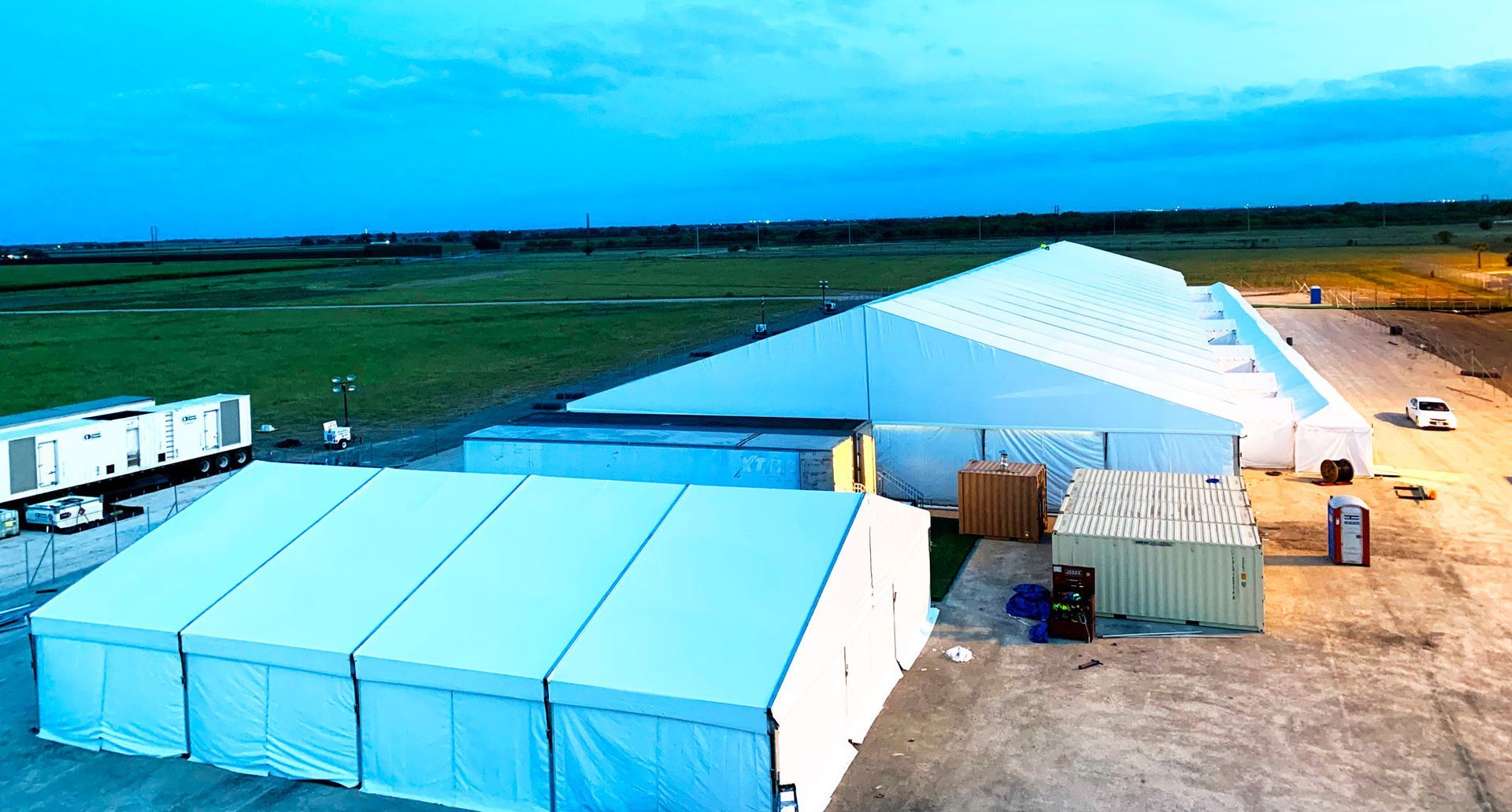 A large white tent is sitting in the middle of a field.