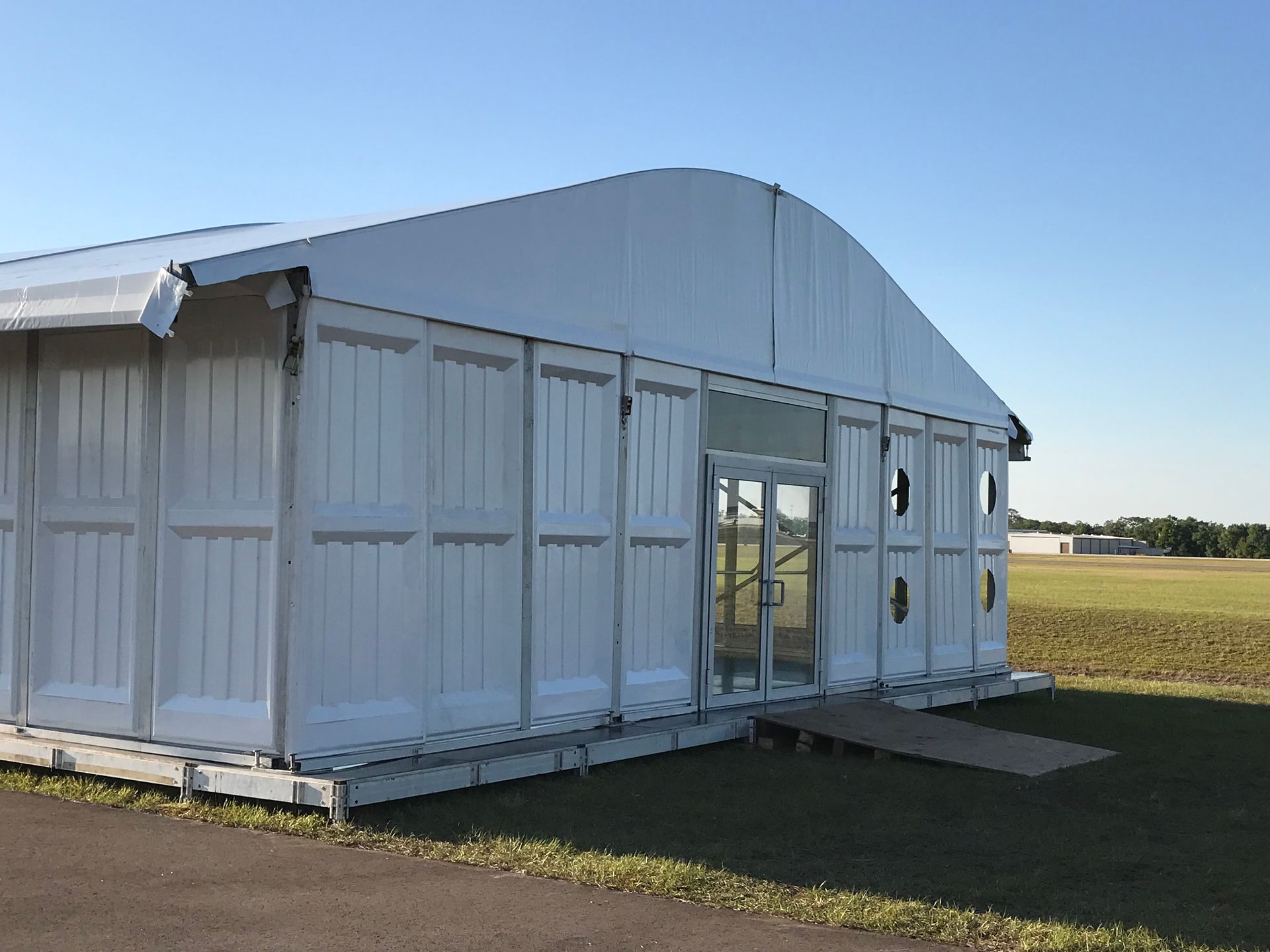 A large white building is sitting in the middle of a field