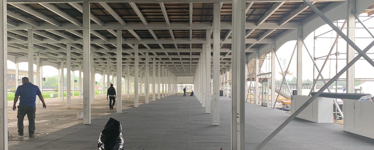 A group of people are walking through a large empty building.
