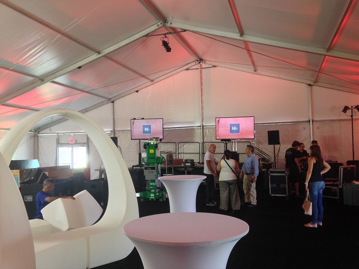 A group of people standing around tables in a tent