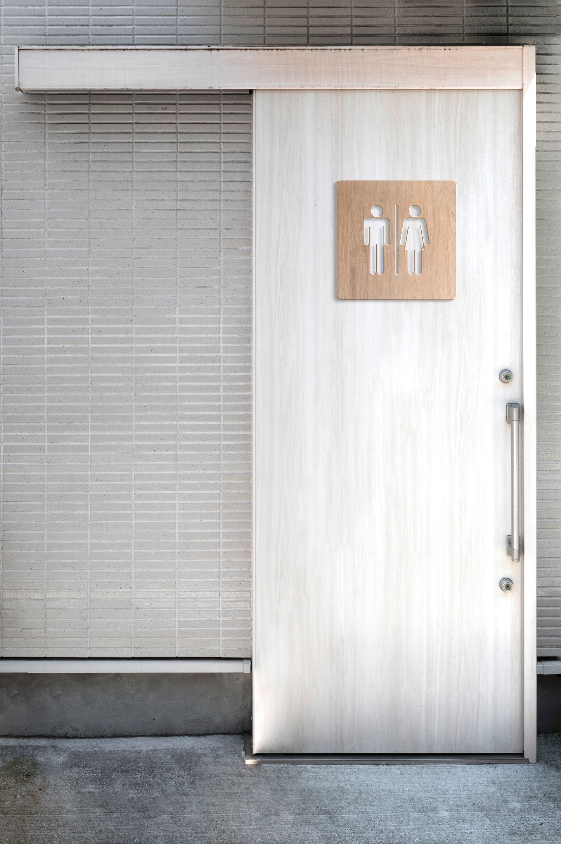 A sliding door to a public restroom with a sign on it.