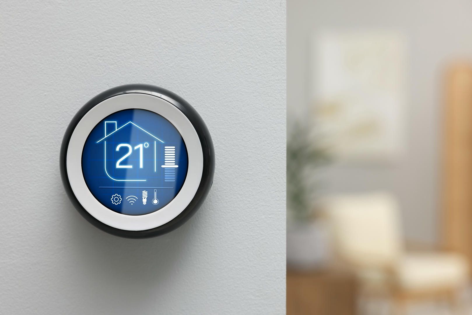 A thermostat on a wall shows the temperature is 21 degrees