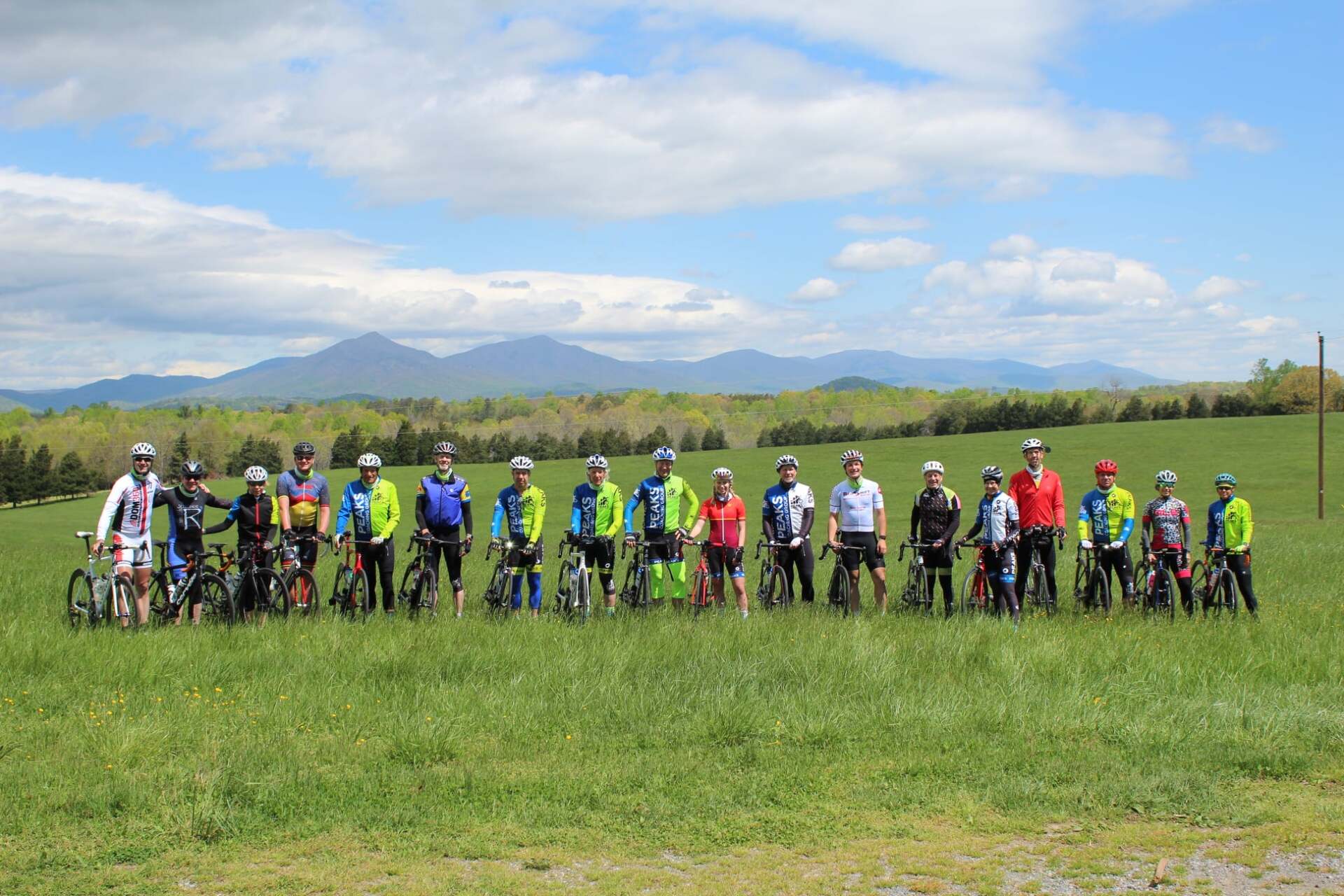 A group of people standing in a field with bicycles.