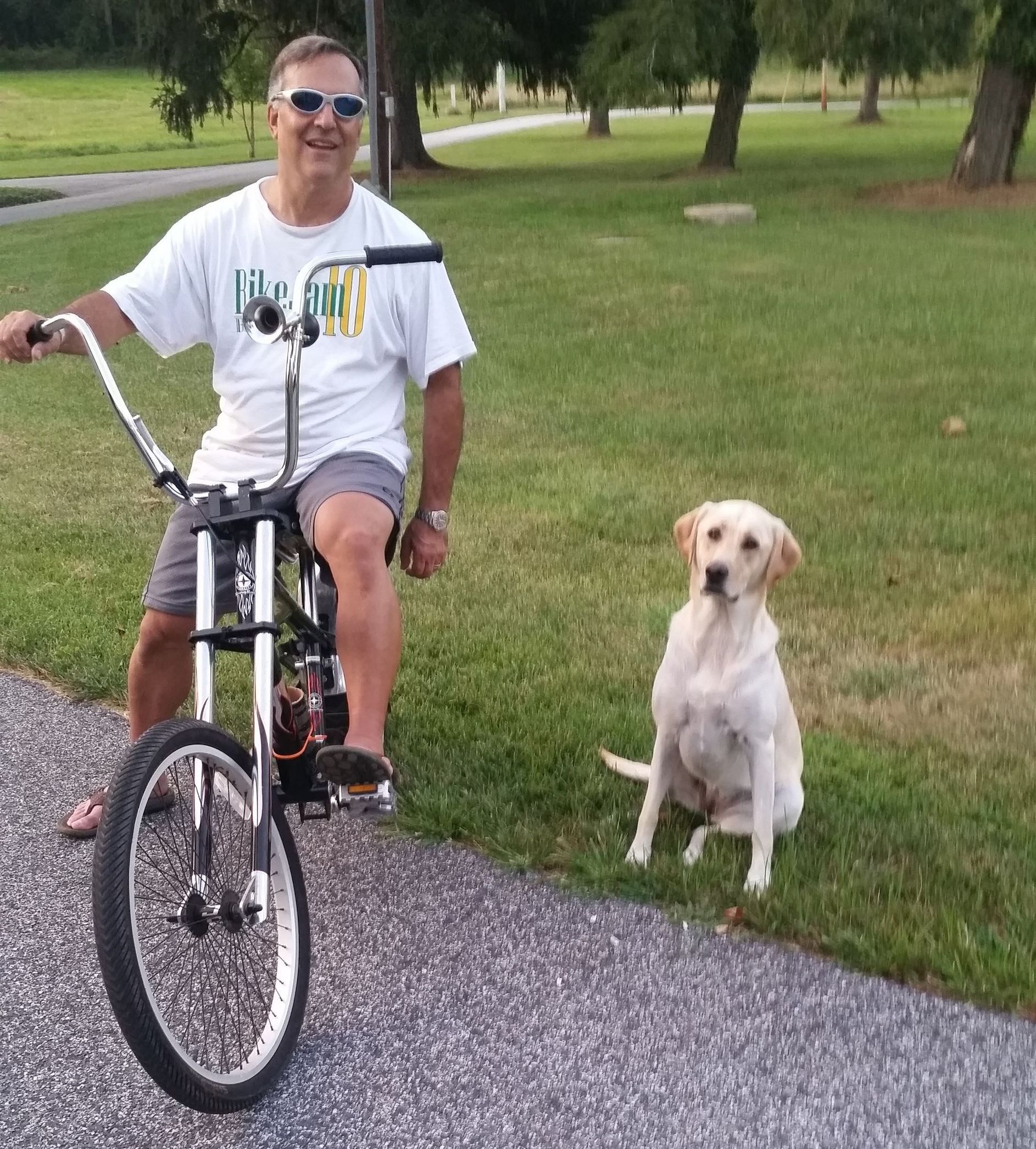 A man is riding a bike with a dog sitting next to him