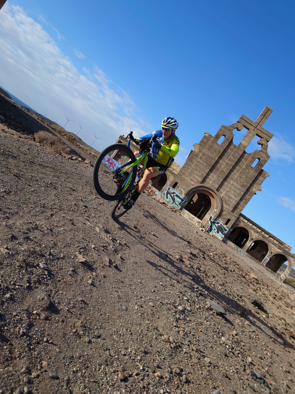 A person is riding a bike on a dirt road in front of a church.