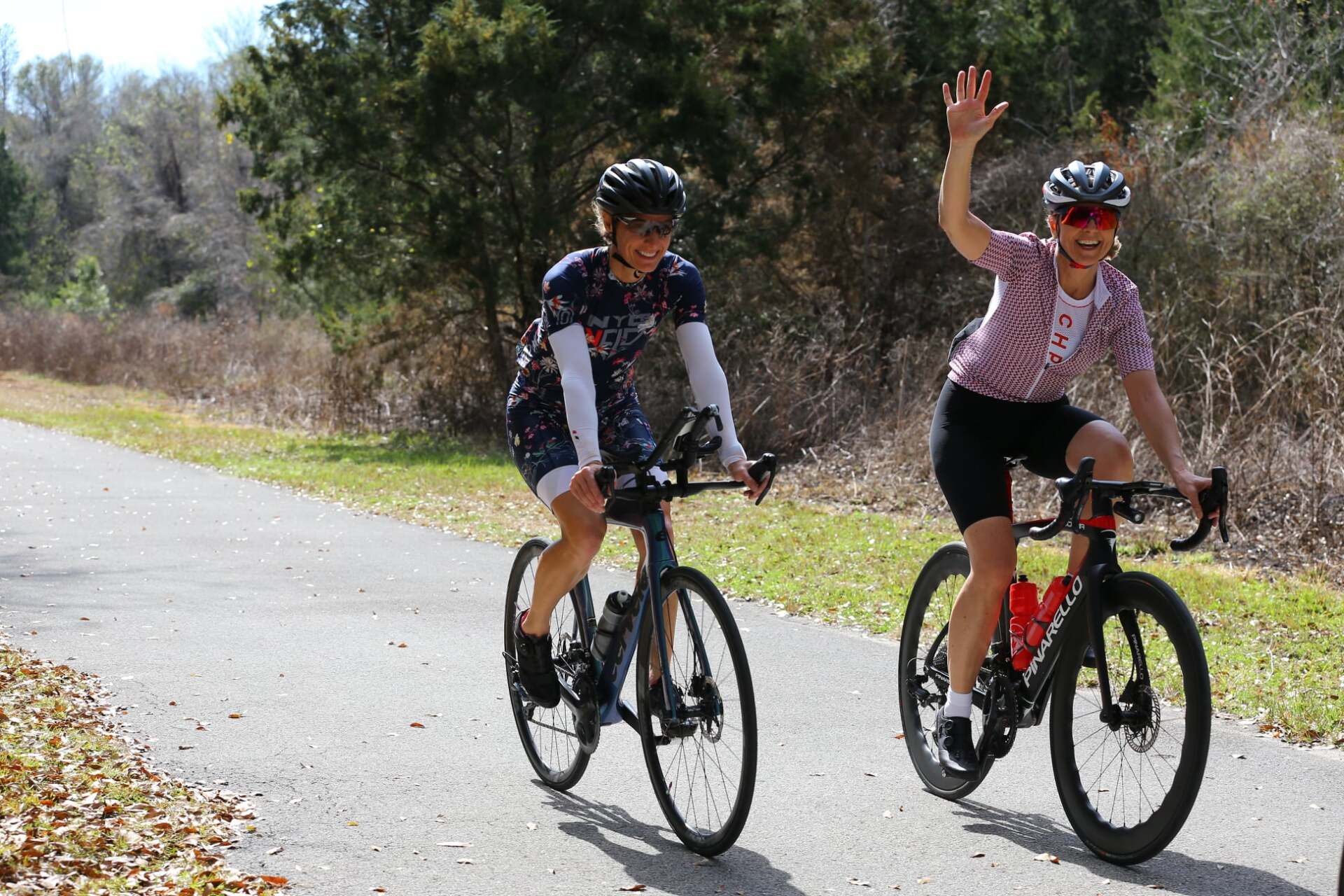 Two women are riding bicycles down a path.