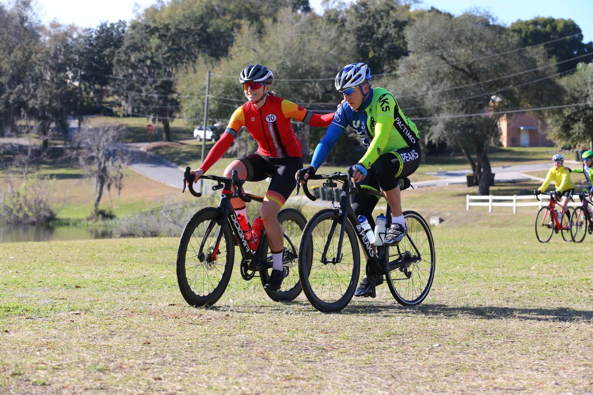 Two men are riding bicycles on a grassy field.