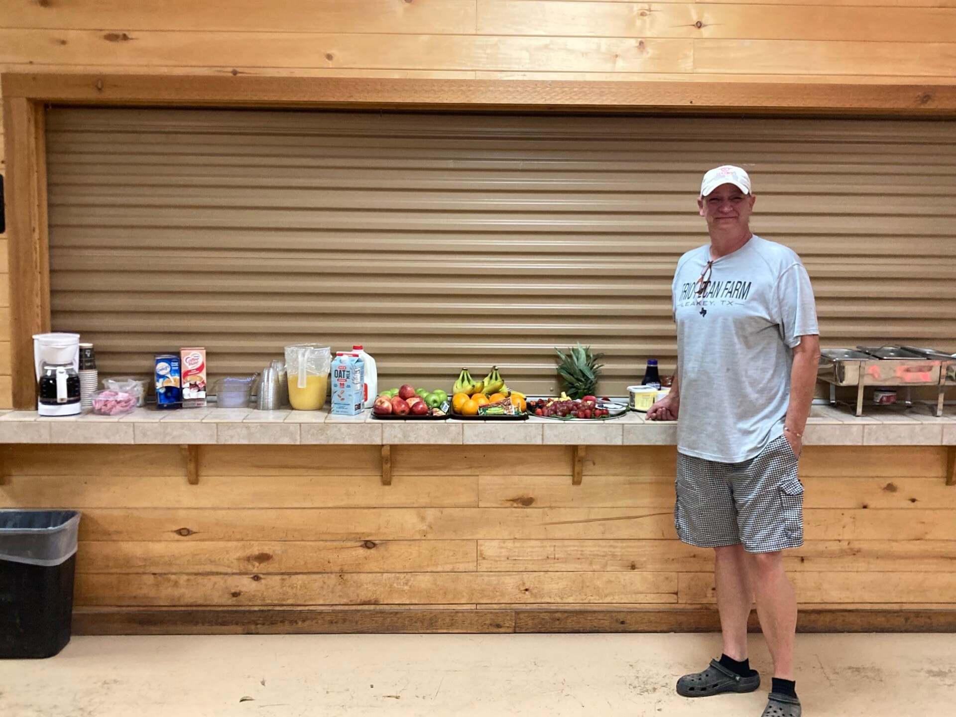 A man is standing in front of a counter with fruit on it.