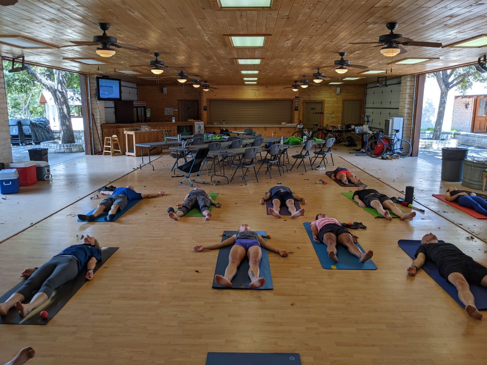 A group of people are laying on yoga mats in a large room.