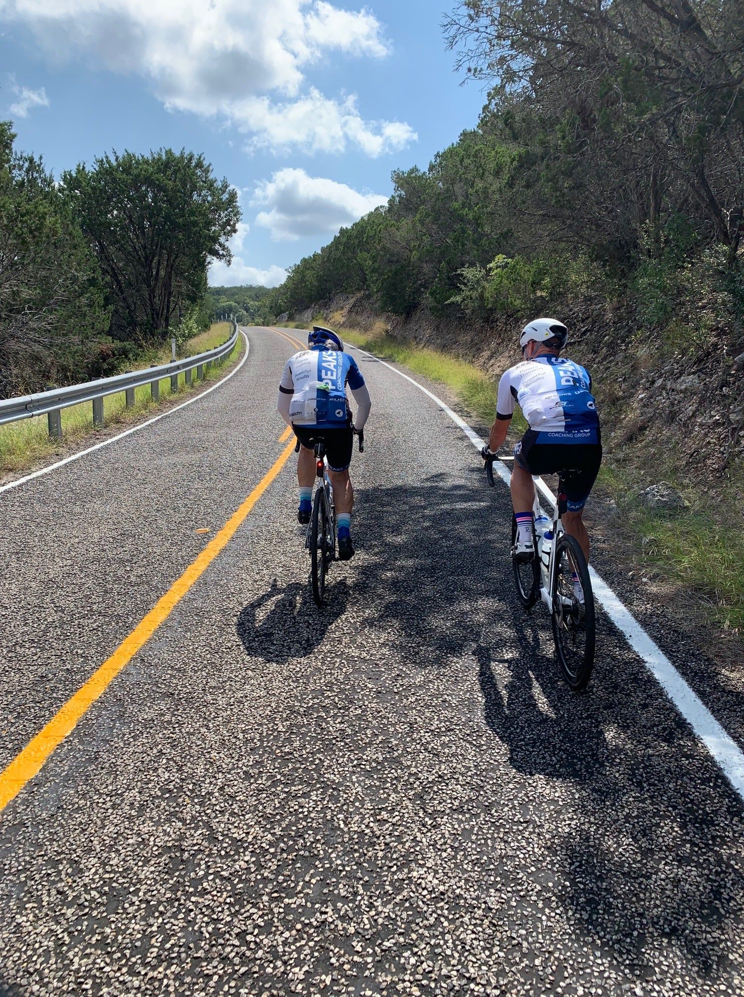 Two people are riding bicycles down a road.